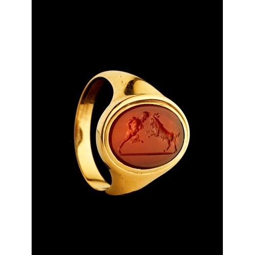 A 18k signet ring set with a Grand Tour carnelian intaglio. Pan fighting a goat.